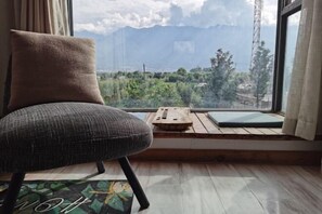 A chair by a window with a view of a mountainous landscape. - Dali Village Inn (Dali City)