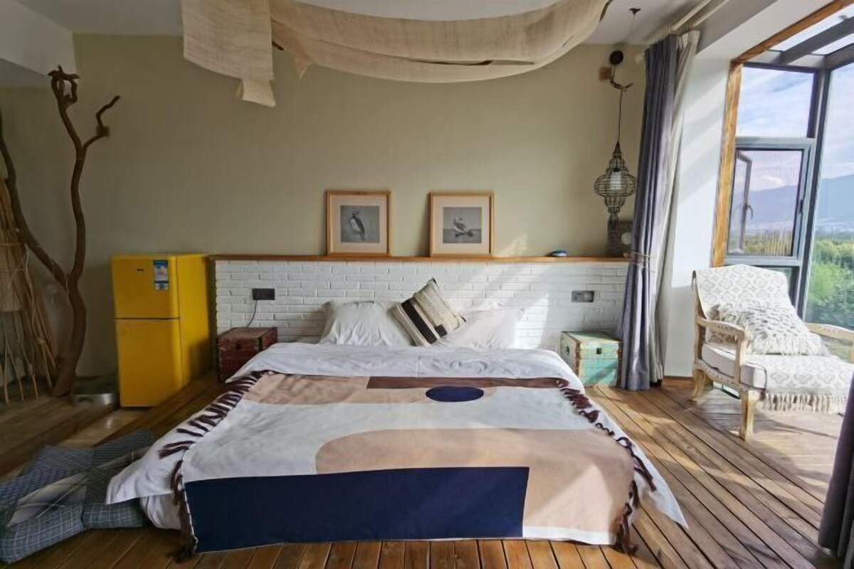 A bedroom with a bed, a chair, a small table, and a window with a view.