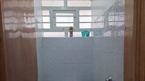 A bathroom with two toilets, a shower, and a window.