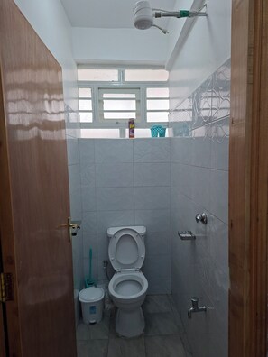 Chuveiro, toalhas de banho, sabonete, papel higiênico