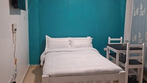 A bedroom with a bed, a desk, and a chair.
