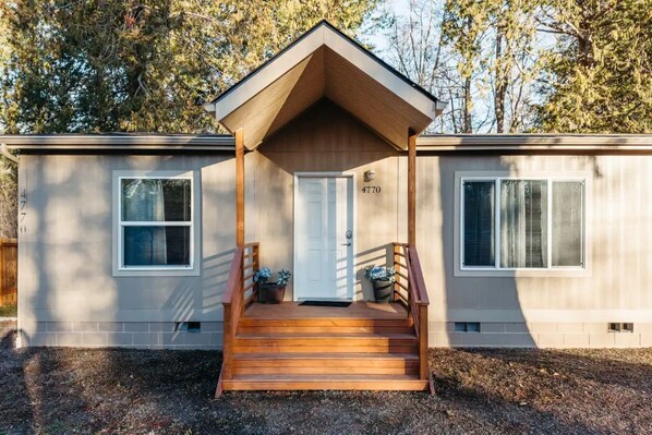A single-story mobile home with a front porch, a door, and two windows.