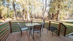 A wooden deck with a glass table and chairs, surrounded by a wooden railing and trees. - Neptune Haven Getaway Near the Ocean  (Ferndale)