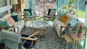 A sunlit room with wicker furniture, a glass table, and a view of the outdoors. - Mod Lodge
Pool open until Sept 20th
Pets Welcome 
EV charging (Edgewood)