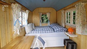 A cozy cabin-style room with a bed, a small table, and a chair. - Sch(l)afgemach Schäferwagen - Farm in the Eifel (Nettersheim)