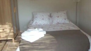 Un dormitorio con una cama, una mesita de noche, una lámpara y un cuadro en la pared.