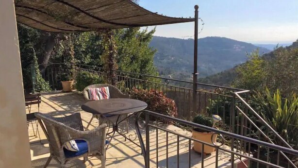 Un patio con una mesa, sillas y una sombrilla, con vistas a las montañas.