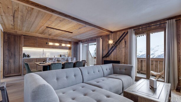 A modern interior with a wooden ceiling, a dining area, a seating area with a sofa, and a view of snow-capped mountains. - Charming apartment for 8 with parking and WIFI near the slopes (Montvalezan-La Rosière)