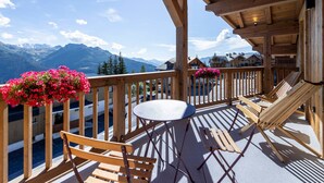 A wooden deck with a table and chairs, overlooking a mountainous landscape. - Charming apartment for 8 with parking and WIFI near the slopes (Montvalezan-La Rosière)
