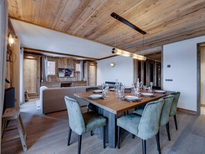 A dining area with a wooden table set for six, surrounded by upholstered chairs.