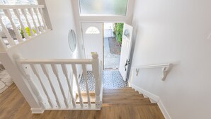 Eine Treppe mit weißen Geländern und Holzboden, die zu einer Tür mit Glasfenster führt.