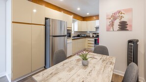 Eine moderne Küche mit integriertem Kühlschrank, Holzschränken und einem Essbereich mit Tisch und Stühlen.