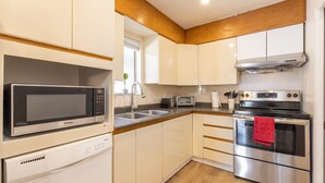 Eine moderne Küche mit weißen Schränken, einer Edelstahl-Mikrowelle, einem Geschirrspüler, einem Herd und einem Toaster.