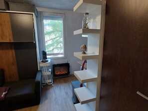 A compact living space with a fireplace, a small table with a globe, and a shelf with decorative items.