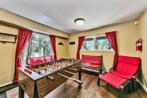 Une pièce avec une table de baby-foot, deux chaises rouges et un extincteur accroché au mur.