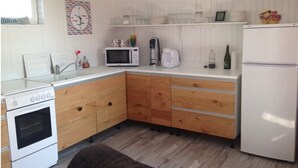 Una cocina compacta con armarios de madera, una estufa blanca, un microondas, una cafetera y un refrigerador.