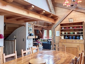 A cozy wooden interior with a dining area, wooden shelves with colorful mugs, and a staircase leading to a loft. - Renovated 3-star chalet, 14 people, Mont Blanc view, Wifi (Cordon)
