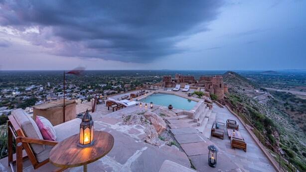 A rooftop pool area with lounge chairs, a table with a lantern, and a view of the surrounding landscape. - Mundota Fort and Palace (Jalsu)