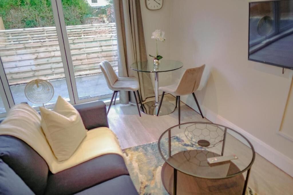 Una sala de estar moderna con un sofá, una mesa de centro de vidrio y un comedor con sillas y una mesa pequeña.