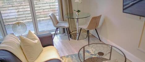 Una sala de estar moderna con un sofá, una mesa de centro de vidrio y un comedor con sillas y una mesa pequeña.