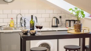 A modern kitchen with a dark countertop, a clock, and a potted plant. - Catharine House by condokeeper (Cambridge)