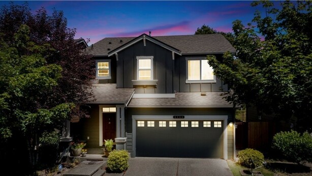 A two-story house with a dark gray exterior, a garage with multiple lights, and a well-maintained front yard with potted plants and a small lawn. - Tacoma House INN W/ Centralized AC (Tacoma)