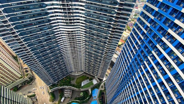 A high-rise building with a curved facade, multiple balconies, and a central courtyard with a swimming pool.