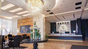 A reception area with a chandelier, reception desk, and seating area. - Freisian for Hotel Apartment (Jeddah)
