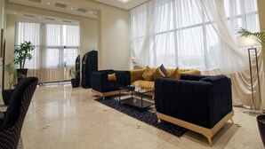 A spacious living room with a sofa set, a coffee table, and a floor lamp. - Freisian for Hotel Apartment (Jeddah)