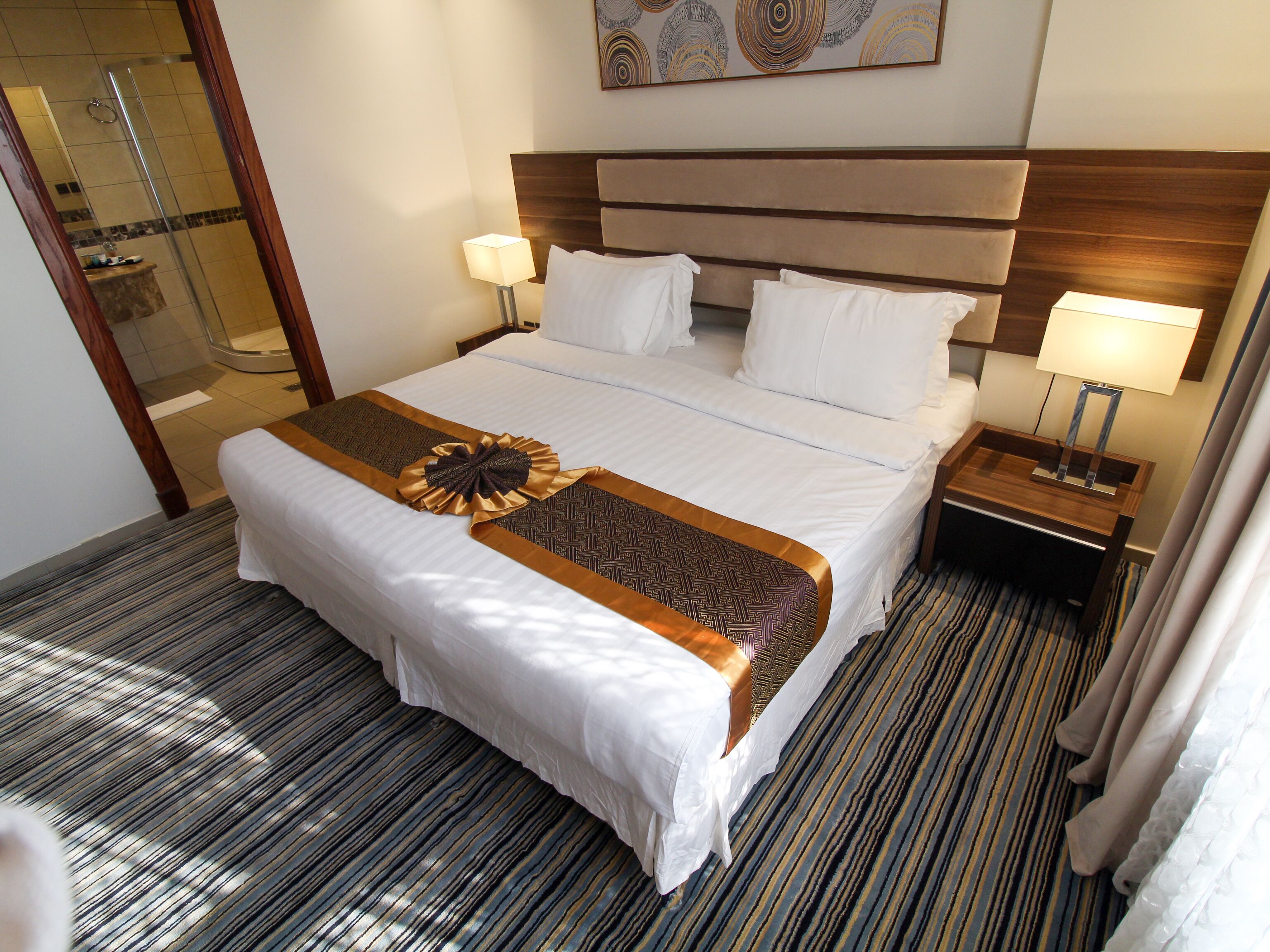Hotelkamer met een groot bed, twee nachtkastjes, een douche en een kunstwerk aan de muur.