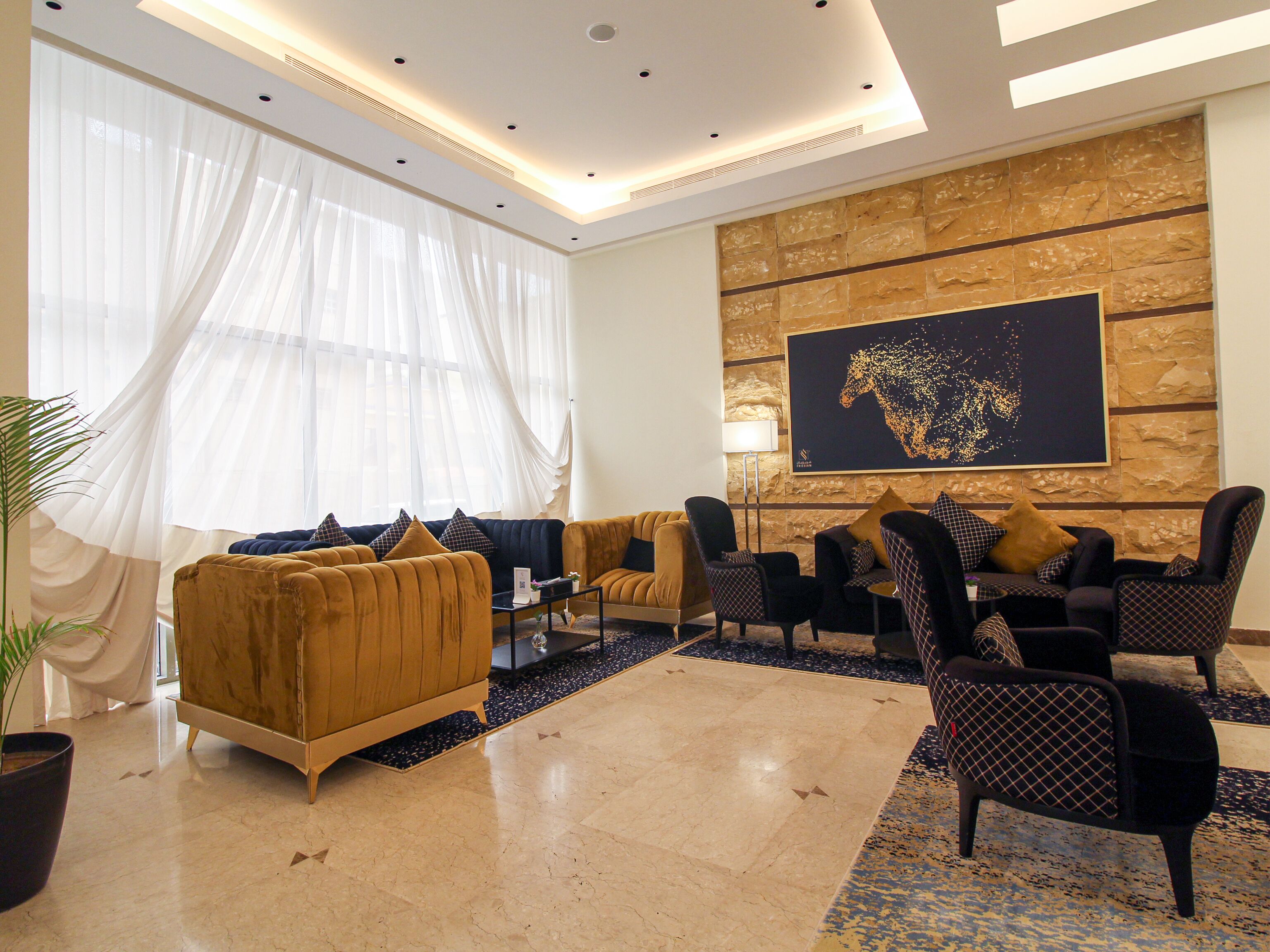 Un salon moderne avec un canapé, des fauteuils, une table basse et un grand tableau abstrait accroché au mur.