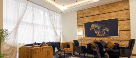Un salon moderne avec un canapé, des fauteuils, une table basse et un grand tableau abstrait accroché au mur.