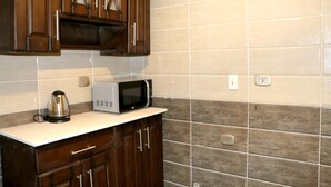 Una cocina con armarios de madera, microondas y hervidor sobre la encimera.