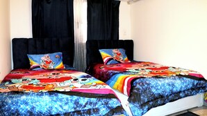 Un dormitorio con dos camas, cada una con una colcha y almohadas a juego con motivos de dibujos animados.