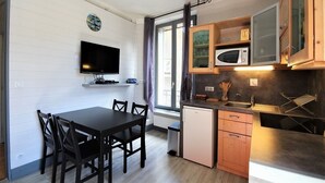 Cozinha compacta com mesa de jantar, cadeiras, micro-ondas e armários.