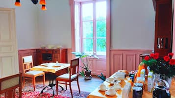 Ein Essbereich mit einem Tisch für vier Personen, einem Fenster mit rosa Fensterläden und einer Kronleuchter.