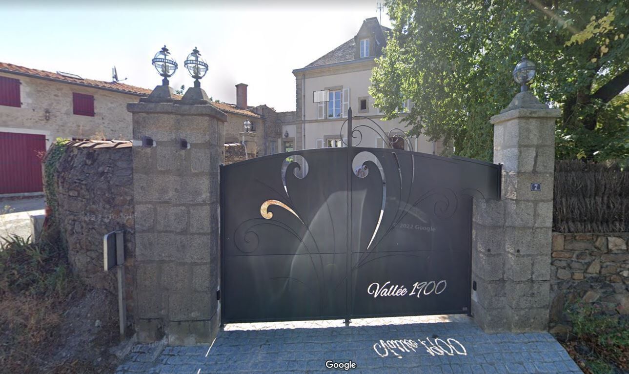 A gated entrance with a stone wall and a metal gate.