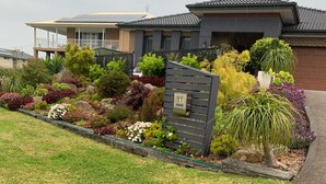 A residential property with a landscaped garden, a mailbox, and a modern house with a solar panel roof. - Entire 1br 50sm guest suite 3mins to beach shops restaurants small dog welcome.
 (Ulladulla)