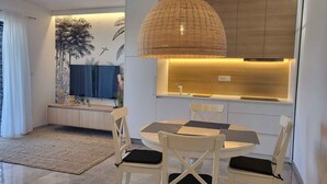 Un comedor moderno con una mesa redonda, sillas blancas y una lámpara colgante de fibras.