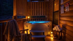Eine Holzhütte mit Whirlpool, einem Sessel und Handtüchern.