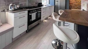 Une cuisine moderne dotée d’un four encastré, d’un réfrigérateur en acier inoxydable et d’un plafond en bois.