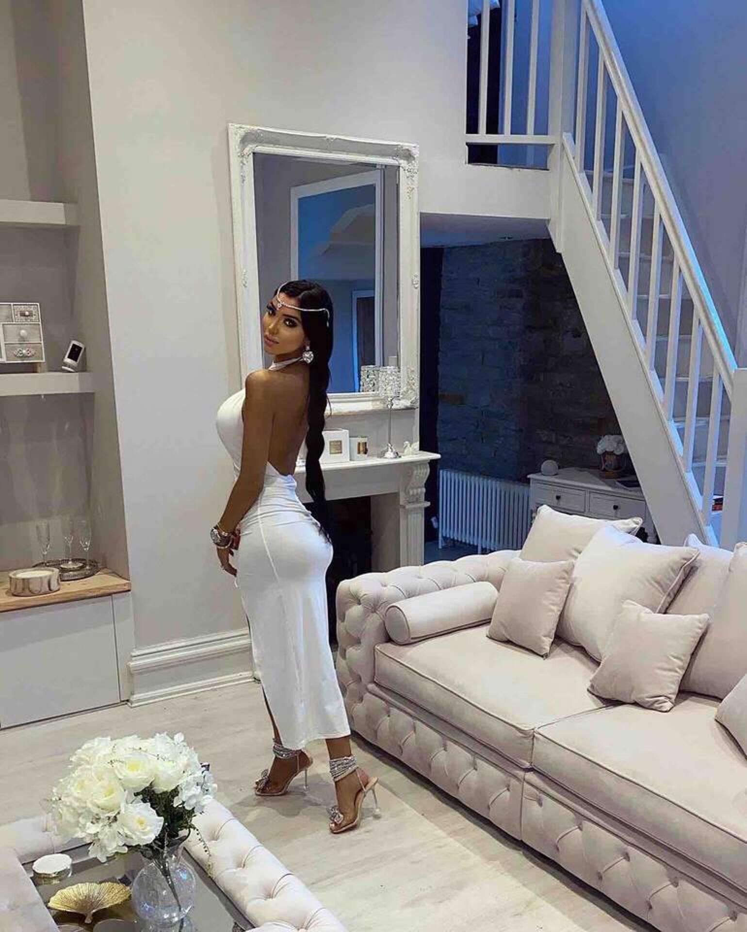 A modern living room with a large mirror, a beige sofa, and a staircase.