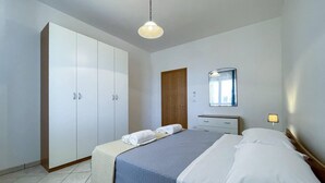 Ein Schlafzimmer mit einem Bett, einem Kleiderschrank, einem Spiegel und einer Nachttischlampe.