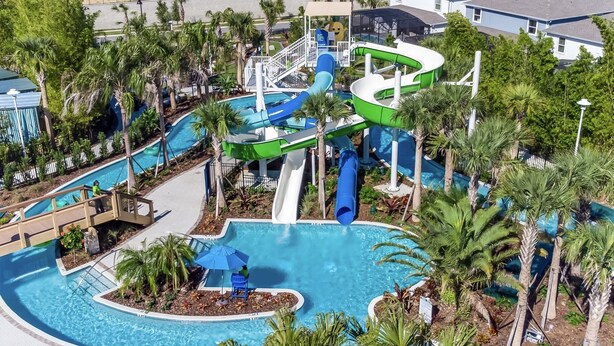 Ein Wasserpark mit mehreren Rutschen und Becken, umgeben von Palmen und einigen Gebäuden im Hintergrund.