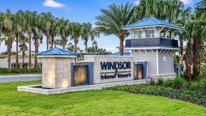 Schild des Windsor Island Resort mit steinernen Pforten, einem Gebäude mit blauer Dachdeckung und Palmen im Hintergrund.