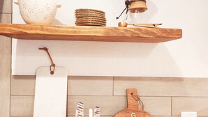 Een keuken met houten planken waarop keukengerei, een snijplank en een messenblok staan.