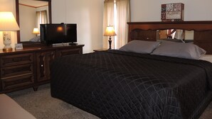 A hotel room with a large bed, a television on a wooden dresser, a mirror, and a framed quote on the wall. - At Home Base IV, 1 of 4 units. You'll feel right at home,1/2 mile to Dreams Park (Milford)