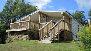 A two-story house with a wooden deck, a covered porch, and a staircase leading to the upper level. - At Home Base IV, 1 of 4 units. You'll feel right at home,1/2 mile to Dreams Park (Milford)