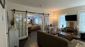 A living room with a sofa, a coffee table, a TV, and a sliding door leading to another room.