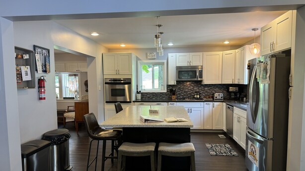A modern kitchen with white cabinets, stainless steel appliances, and a central island with bar stools.